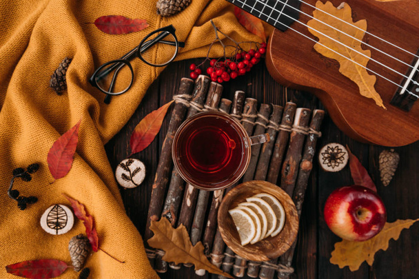 Flat lay. Textured scarf with cup of tea . Autumn leaves on wooden background . Autumn or Winter concept. - Zdjęcie, obraz