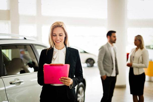 Professional beautiful saleswoman working in car dealership - Photo, image