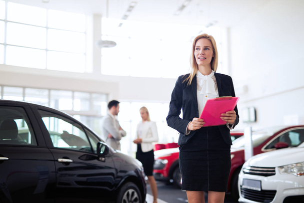 Young beautiful female car sales consultant working in showroom - Fotografie, Obrázek