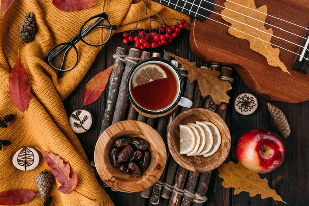 Flat lay. Textured scarf with cup of tea . Autumn leaves on wooden background . Autumn or Winter concept. - Foto, afbeelding