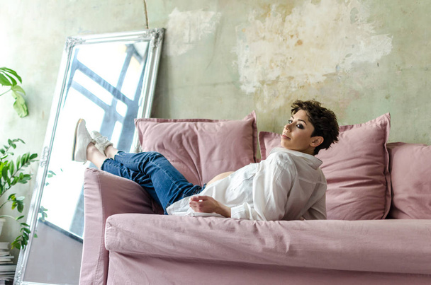 Kaunis raskaana oleva nainen istuu sohvalla kotona
 - Valokuva, kuva