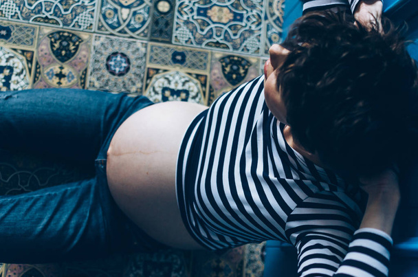 Pregnant smiling woman sitting on wooden floor in room. . Maternity. Motherhood. - Photo, image