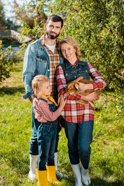 famille d'agriculteurs avec petite fille et lapin brun à l'extérieur
 - Photo, image