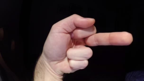 Nahaufnahme einer männlichen Hand, die Mittelfinger-Geste auf schwarzem Hintergrund zeigt - Filmmaterial, Video