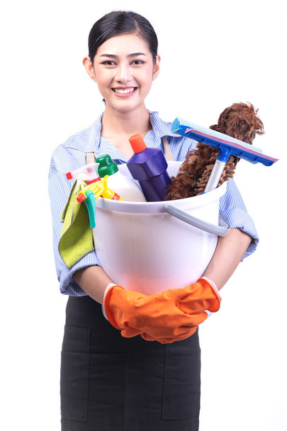 House cleaning service woman isolated in white. Asian young woman with gloves, happy smile, holding bucket full of cleaning items. House cleaning service concept. - Photo, Image