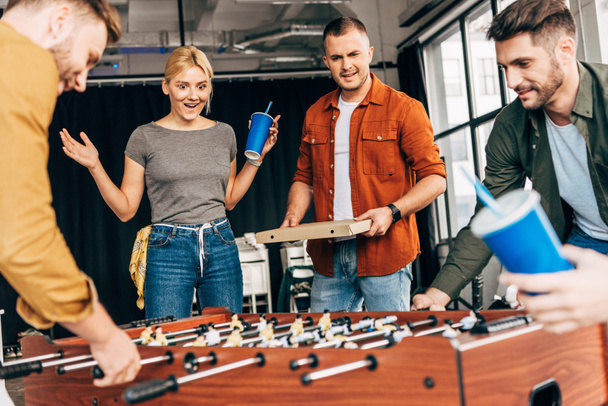 group of happy casual business people playing table football with pizza at office and having fun together - Foto, Imagem