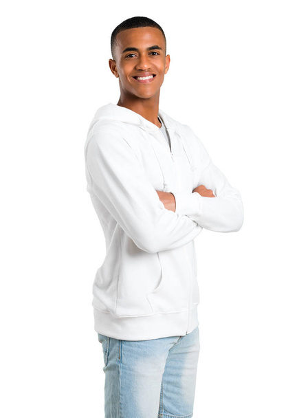 Sötét bőrű fiatalember fehér pulóver, miközben mosolyogva az oldalsó karba vezetése. Magabiztos kifejezés elszigetelt fehér background - Fotó, kép