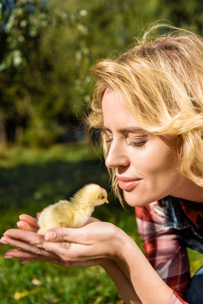 smiling woman holding adorable yellow baby chick outdoors  - Photo, Image