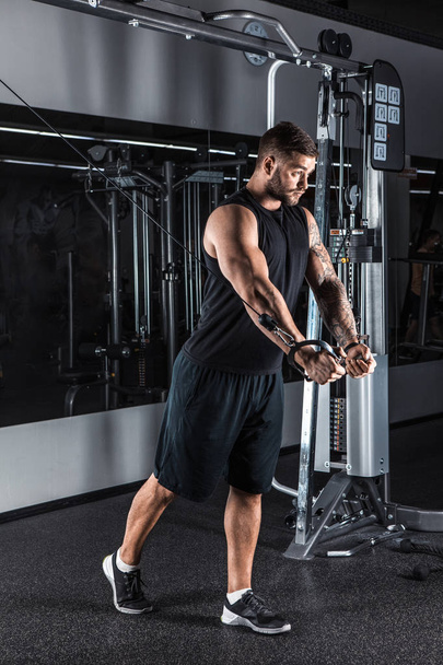 Handsome bodybuilder works out pushing up excercise in gym - Foto, imagen