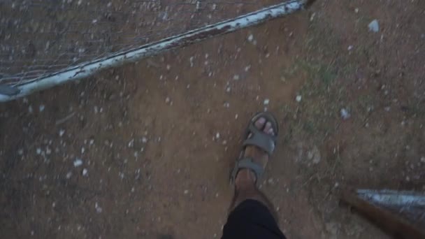 Tiro subjetivo dos pés de um homem com sandálias andando na terra do campo
  - Filmagem, Vídeo