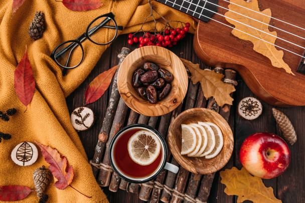 Flat lay. Textured scarf with cup of tea . Autumn leaves on wooden background . Autumn or Winter concept. - Foto, imagen