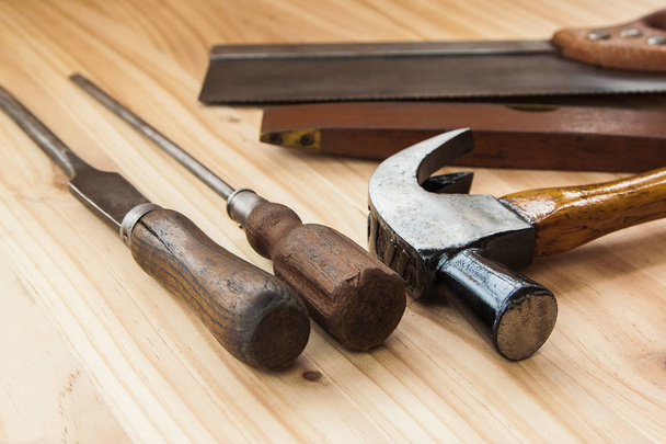 Antigua herramienta de madera vintage sobre fondo de madera, martillo de sierra, destornillador mango artesanía
. - Foto, imagen
