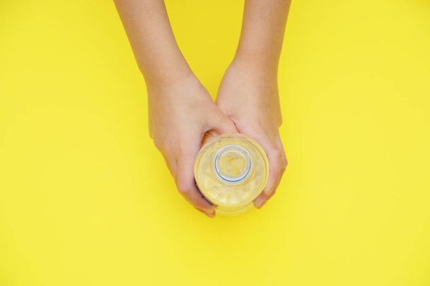 bottle of pure water in hands on yellow background with copy space on top. - 写真・画像