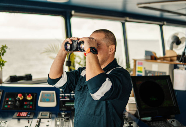 Navigational officer lookout on navigation watch looking through binoculars - Photo, Image