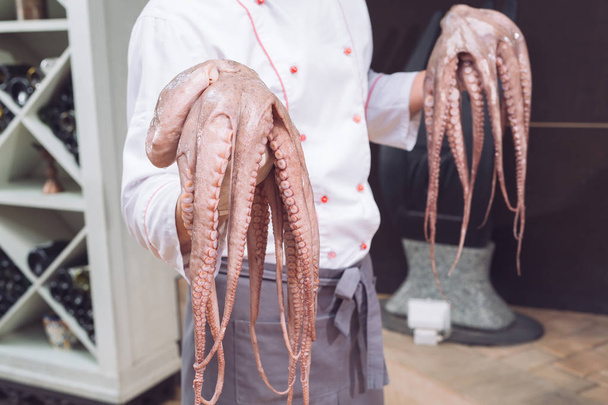 closeup of chef holding fresh raw octopus. - Fotó, kép