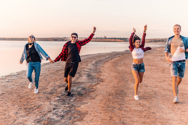 young hipster friends on beach running together - 写真・画像