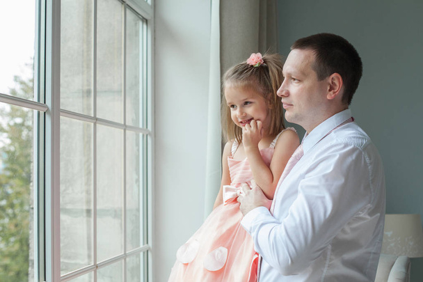 Vader en dochter kijken venster samen thuis - Foto, afbeelding