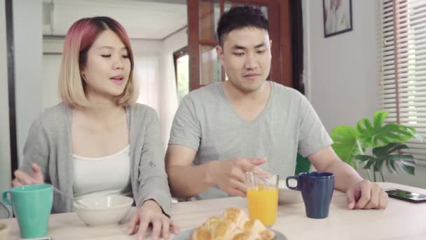 Šťastný sladké Asijské pár snídáš, obilovin s mlékem, chléb a pít pomerančový džus po probuzení v dopoledních hodinách. Manžel a jeho žena jíst potraviny dohromady. - Záběry, video