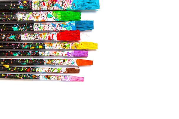 Artistic background. Artist paintbrushes with colourful paint stains isolated on white background with copy space - Photo, Image