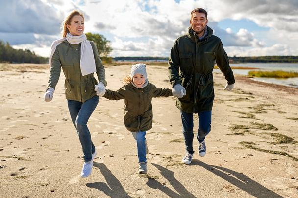 happy family running along autumn beach - Foto, immagini