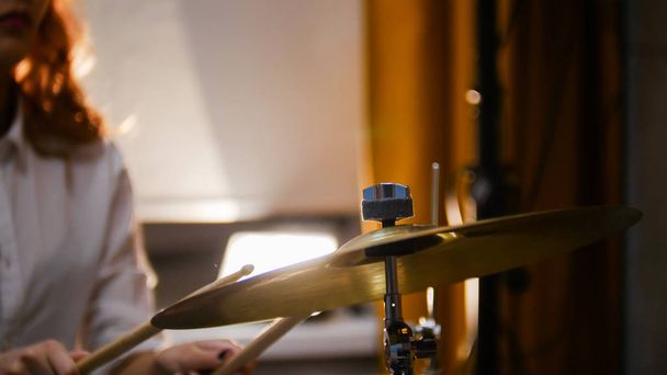 Repetition. Ginger girl plays drums. The girl hitting hi-hat. - 写真・画像