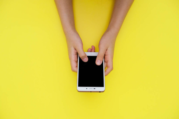 Smartphone in der Hand auf gelbem Hintergrund mit Kopierraum oben. - Foto, Bild