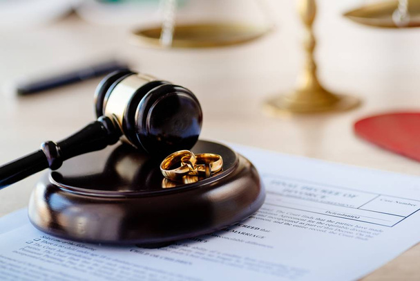 Divorce decree in and two broken wedding rings on judge gavel. Divorce and separation concept - Photo, Image