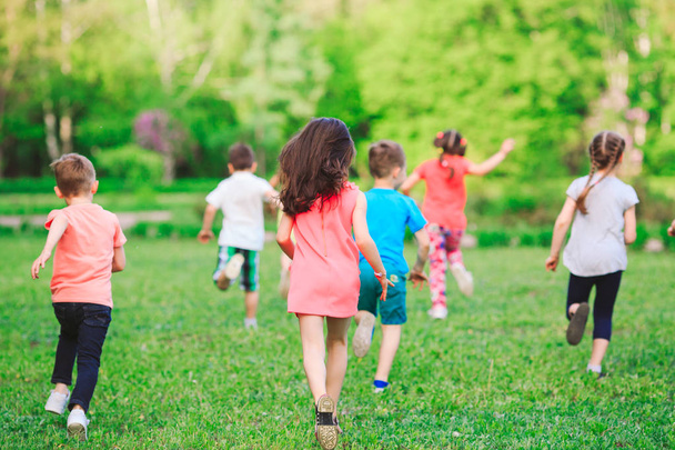 viele verschiedene Kinder, Jungen und Mädchen, die an sonnigen Sommertagen in Freizeitkleidung durch den Park laufen - Foto, Bild