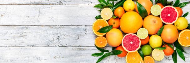 Hintergrund sind frische Zitrusfrüchte. Orange, Grapefruit, Zitrone, Limette, Mandarine. Zitrusfrüchte mit Blättern vermischen. Langes Webformat. Kopierraum - Foto, Bild