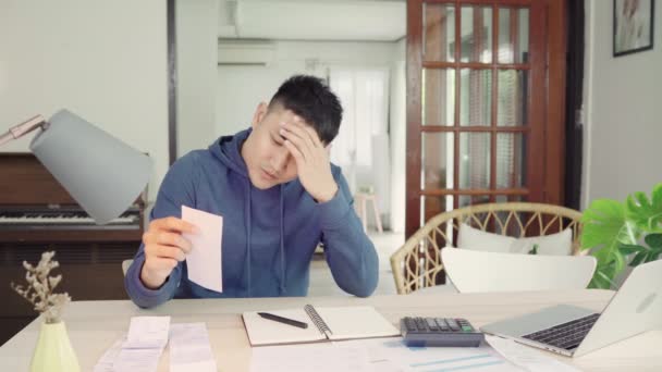 Young stressed asian couple managing finances, reviewing their bank accounts using laptop computer and calculator at modern home. Woman and man doing paperwork together, paying taxes online. - Footage, Video