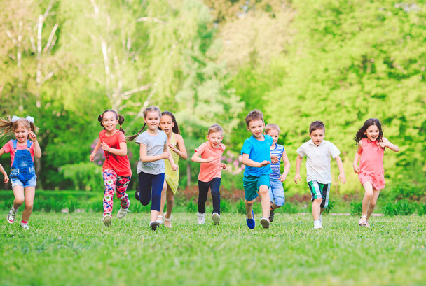 Багато різних дітей, хлопчиків і дівчаток біжать в парку в сонячний літній день в повсякденному одязі
 - Фото, зображення