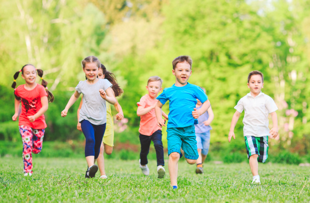 Багато різних дітей, хлопчиків і дівчаток біжать в парку в сонячний літній день в повсякденному одязі
 - Фото, зображення