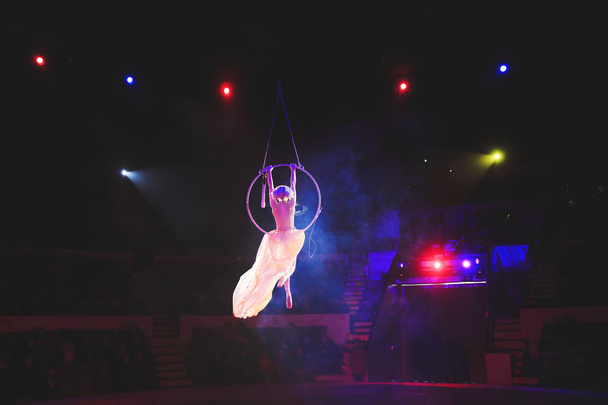 Aerial acrobat in the ring. A young girl performs the acrobatic elements in the air ring. - Фото, изображение