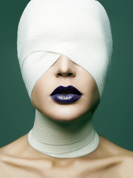 Dziewczyna Glamour maski na halloween. twarz kobiety owinięte w bandaż. uroda makijaż Kobieta, niebieski szminki. Chirurgia plastyczna - Zdjęcie, obraz