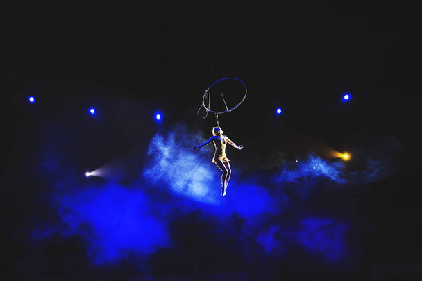 Aerial acrobat in the ring. A young girl performs the acrobatic elements in the air ring. - Photo, image