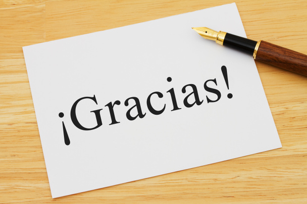 spanische Danksagung, eine weiße Karte auf einem Schreibtisch mit einem Stift mit Text gracias - Foto, Bild