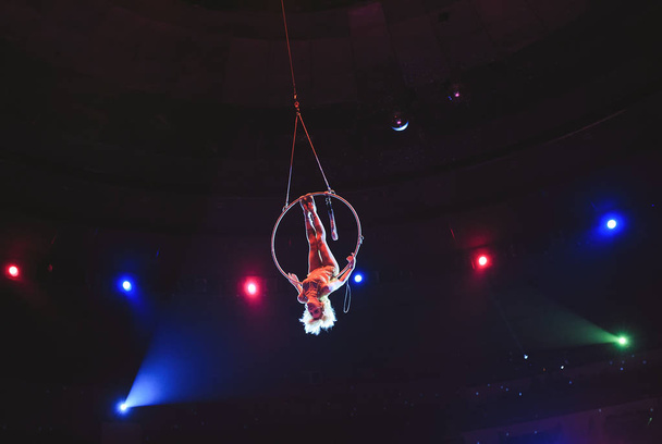 Aerial acrobat in the ring. A young girl performs the acrobatic elements in the air ring. - Foto, immagini