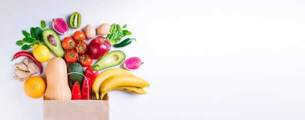 Healthy food in paper bag fruits and vegetables on white. Concept healthy food background. Vegetarian food. Shopping food supermarket. Long web format - 写真・画像