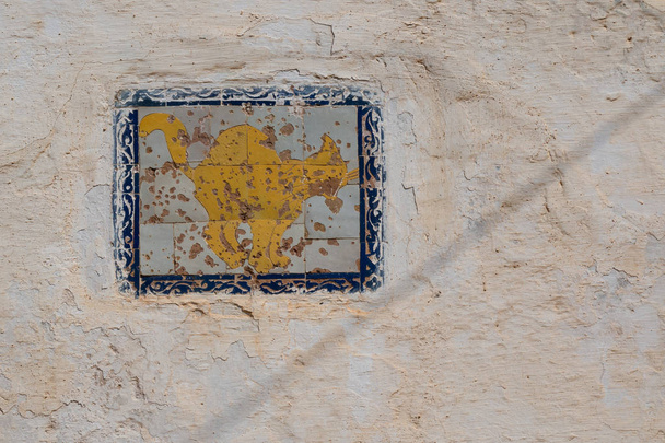 alte strukturierte und verwitterte Hauswand mit Ziegel, Katzenmotiv in gelber Farbe und blauem Rahmen. kasbah de oudaias, rabat, Marokko. - Foto, Bild