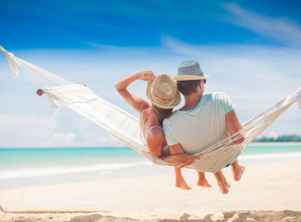 Young couple in love relaxing in a hammock by the beach - Фото, изображение