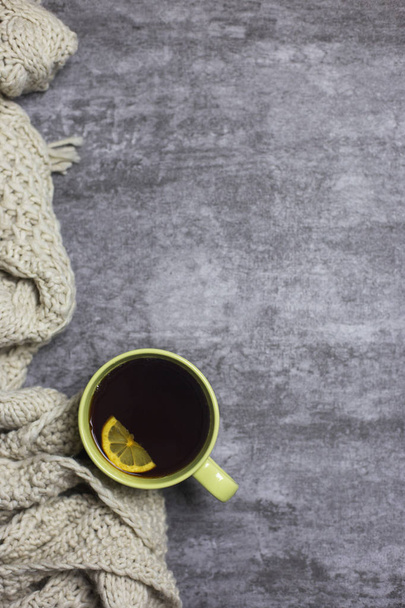 Tea with lemon in tea cup and knitted scarf at gray background - 写真・画像