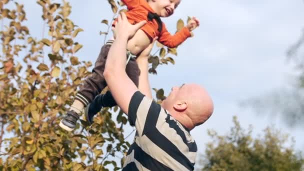 Концепция счастливой семьи. Отец подбрасывает своего очаровательного сына в воздух
. - Кадры, видео