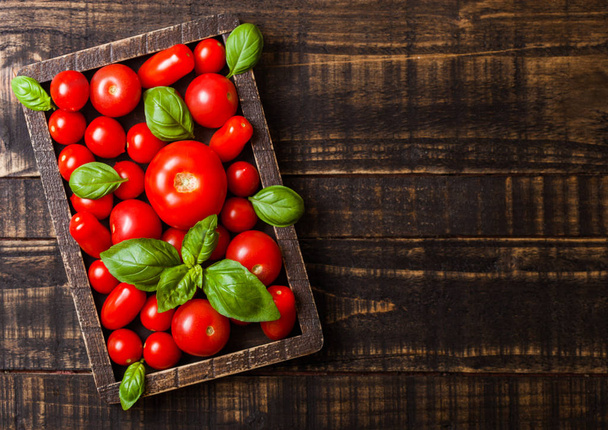 Organic Tomatoes with basil and pepper in vintage wooden box on wooden table - Фото, изображение