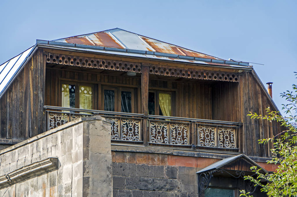 Ancien bâtiment en pierre avec beau balcon en bois sous le ciel bleu à Gyumri, Arménie
 - Photo, image