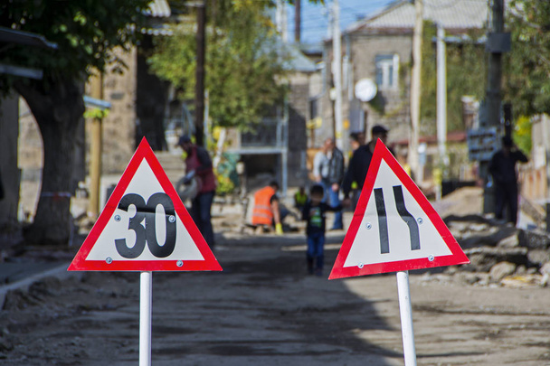 Un chantier routier est protégé par des panneaux d'avertissement. Travailleurs sur fond flou. Gyumri, Arménie
 - Photo, image