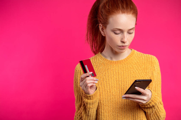 Portrait of cute ginger girl using smartphone isolated on pink b - Foto, Bild