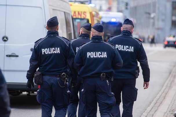 Polis memuru sokakta yürüyen grubu. Polis işaretiyle mavi üniforma giymiş. - Fotoğraf, Görsel