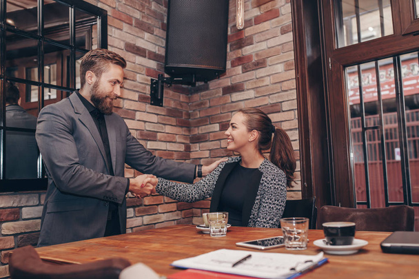 Happy young candidate shaking hands with her employer after a job interview, employment and business meetings concept - Photo, image