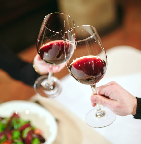 Man and woman drinking red wine. In the picture, close-up hands with glasses.  - Foto, Imagen