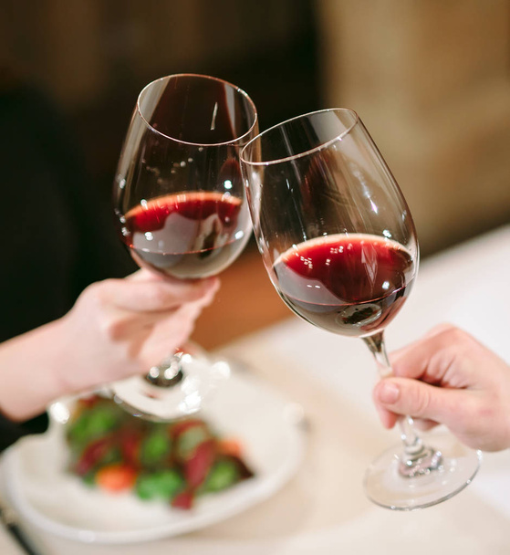 Homme et femme buvant du vin rouge. Sur la photo, mains en gros plan avec des lunettes.  - Photo, image
